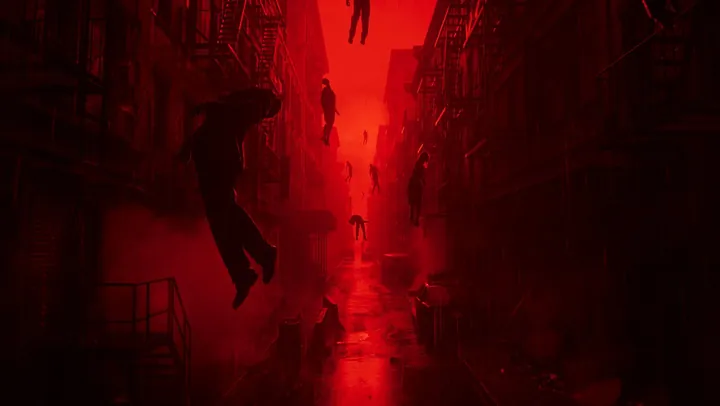 Un callejón de Manhattan bañado en luz roja, con escaleras de incendios en los edificios de ambos lados y figuras humanas suspendidas en el aire como si la gravedad hubiera dejado de actuar, mientras el pavimento mojado refleja el resplandor rojo