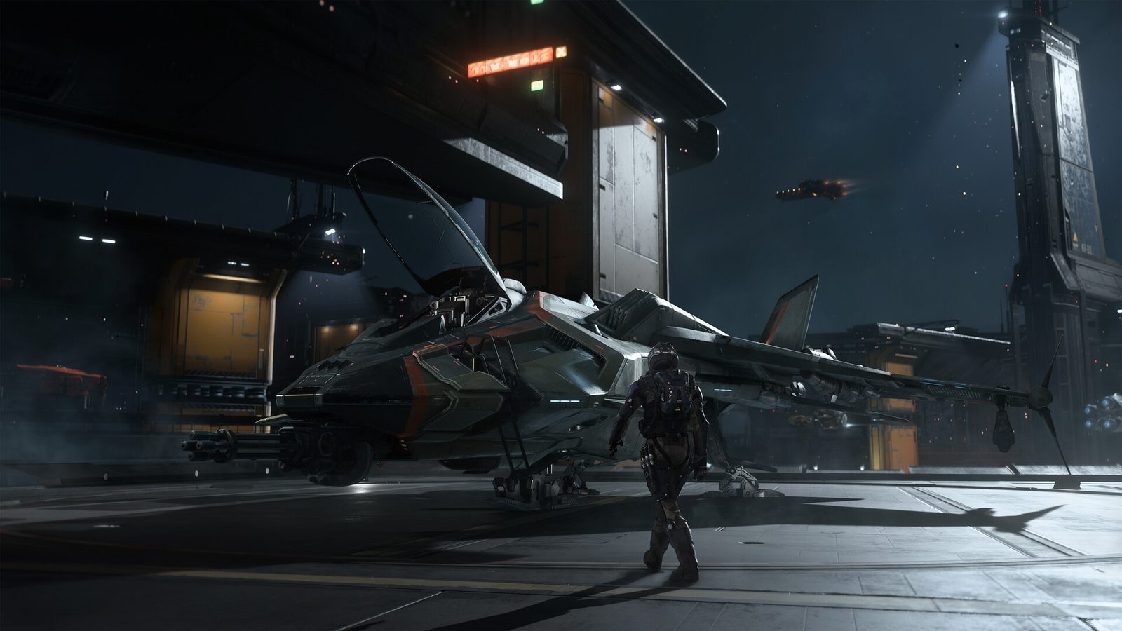 Una captura de Squadron 42 en Steam muestra a un soldado con traje espacial caminando junto a un caza posado sobre el suelo oscuro de un hangar, mientras otra nave cruza el cielo